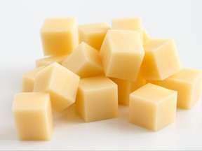 Cubes of yellow cheese stacked randomly on white.