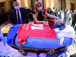 Argentina's first lady Fabiola Yanez places flowers on the casket of soccer legend Diego Maradona as President Alberto Fernandez looks on, at the presidential palace Casa Rosada, in Buenos Aires, November 26, 2020.