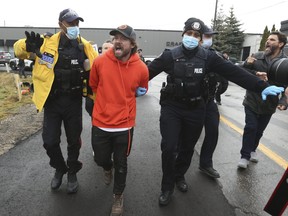 Adamson BBQ owner Adam Skelly is led away from his restaurant just after noon time by Toronto Police on November 26, 2020. J