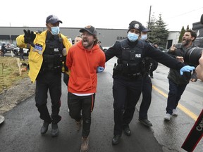 Adamson BBQ owner Adam Skelly is led away from his restaurant just after noon time by Toronto Police. Protestors and supporters tried to wrestle him away from police as they brought him to an awaiting cruiser on Royal York Blvd. on Thursday November 26, 2020. Jack Boland/Toronto Sun/Postmedia Network