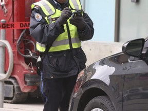 File photo of a parking enforcement officer preparing a ticket in downtown Toronto on March 17 2020.