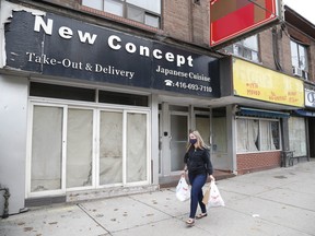 People walking on Queen St E., near Wheeler Ave. in the Beaches, pass empty stores on Oct. 22, 2020.