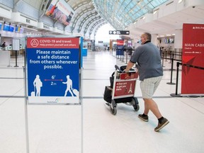 A man pushes a baggage cart wearing a mandatory face mask as a "Healthy Airport" initiative is launched for travel, taking into account social distancing protocols to slow the spread of the coronavirus disease at Toronto Pearson International Airport in Toronto, June 23, 2020.