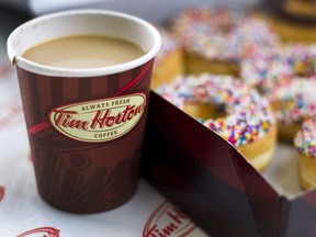A cup of Tim Hortons Inc. coffee and doughnuts are arranged for a photograph in Toronto, Ontario, Canada, on Wednesday, Aug. 3, 2011. Tim Hortons Inc. is a chain of franchise fast food restaurants that serve coffee drinks, tea, soups, sandwiches, donuts, bagels, and pastries. Photographer: Brent Lewin/Bloomberg ORG XMIT: POS2013042413020206