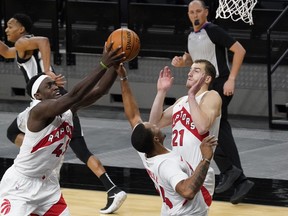 Raptors forward Pascal Siakam (43) grabs a rebound as guards Matt Thomas (21) and Norman Powell (24) look on during the second quarter against the Spurs in San Antonio on Saturday night.