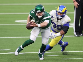 Jets QB Sam Darnold scrambles out of the pocket as Rams' Aaron Donald gives chase.