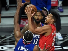 Portland Trail Blazers guard CJ McCollum (3) puts up a shot between LA Clippers forward Kawhi Leonard (2) and guard Paul George (13) during the first quarter at Staples Center in Los Angeles, Calif., Dec. 30, 2020.