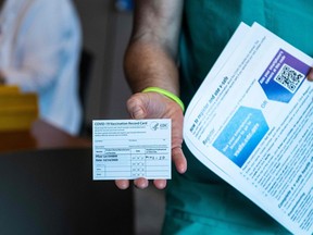 Dan Lacey, a medic at Memorial Healthcare System, shows his vaccination record card after receiving a Pfizer-BioNtech Covid-19 vaccine from Cheryl Birmingham at Memorial Healthcare System, in Miramar, Florida on December 14, 2020.