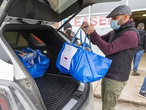 Steven Gougoulias of tlhe London Basket Brigade loads  a volunteers car with baskets of food in London, Ont.