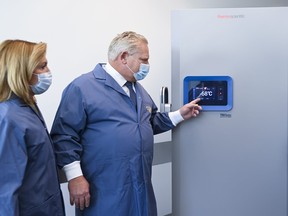 Ontario Premier Doug Ford, right, and Health Minister Christine Elliott look at freezers ahead of COVID-19 vaccine distribution in Toronto, Dec. 8, 2020.