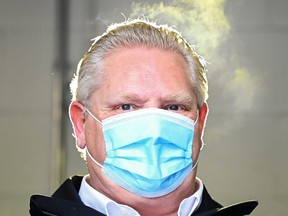 Steam rises and is highlighted from a yellow light, comes off the head of Ontario Premier Doug Ford as he visits the distribution of the Moderna COVID-19 vaccine at the Trillium Health Partners Hospital during the COVID-19 pandemic in Mississauga, Ont., on Wednesday, December 30, 2020. THE CANADIAN PRESS/Nathan Denette