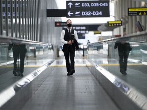 A masked man rides an escalator at Pearson International Airport on June 23, 2020.