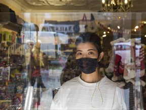 Elsie Hung, co-owner of of La Di Da Boutique along the Danforth, assists customers from behind a plexiglass barrier as the Broadview-Danforth BIAÊorganized a Think Outside the Big Box event during the noon hour to draw attention to the struggles facing small businesses during the lockdown in Toronto, Ont. on Friday December 11, 2020.
