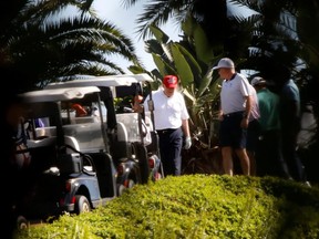 U.S. President Donald Trump (red hat) plays golf at the Trump International Golf Club in West Palm Beach, Fla., Sunday, Dec. 27, 2020.