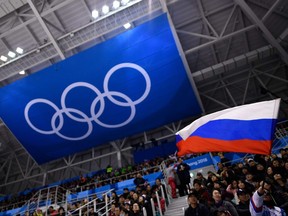 In this file photograph taken on Feb. 16, 2018, a spectator waves a Russian flag in front of The Olympic Rings during the men's preliminary round ice hockey match between the Olympic Athletes from Russia and Slovenia during the Pyeongchang 2018 Winter Olympic Games.