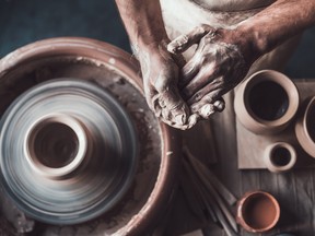 Top view of potter standing near pottery wheel and holding hands together