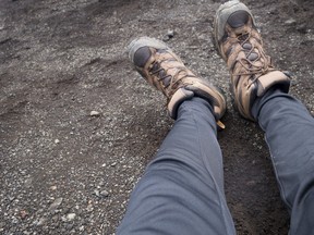 A hiker rests his feet on a trail.