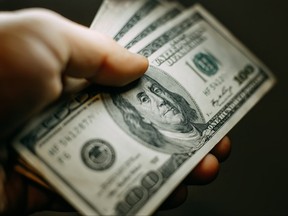 A person holds $100 U.S. dollar bills in this file photo.