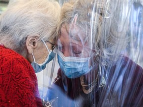 A resident, left, of the Domenico Sartor nursing home in Castelfranco Veneto, near Venice, hugs her visiting daughter through a plastic screen in a so-called "Hug Room" amid the new coronavirus pandemic.