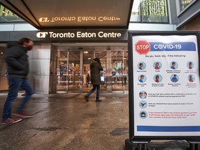 In this file photo, people arrive at the entrance to the Toronto Eaton Centre in downtown Toronto, on November 23, 2020, the first day of a new lockdown in the city.