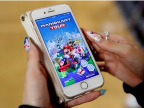 A woman shows the mobile title Mario Kart Tour on her smartphone during an interview with Reuters at Tatio's game center in Tokyo, Japan September 25, 2019.