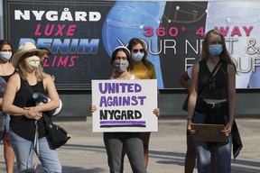 People hold signs at the Time's Up Nygard protest against Canadian fashion mogul Peter Nygard in Winnipeg on Wednesday, Aug. 26, 2020. THE CANADIAN PRESS/Kelly Geraldine Malone