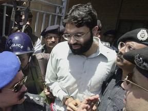 In this photograph taken on March 29, 2002, Pakistani police surround Ahmed Omar Saeed Sheikh as he leaves a court in Karachi.