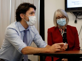 Prime Minister Justin Trudeau, with Minister of Health Patty Hajdu, holds an empty COVID-19 vaccine vial after the first vaccinations were given at the Civic Hospital in Ottawa, Dec. 15, 2020.