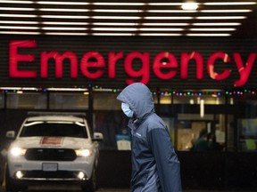 A person wears a protective face mask to help prevent the spread of COVID-19 as they walk past the emergency department of the Vancouver General Hospital, in Vancouver, Wednesday, Nov. 18, 2020.