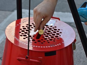 A man puts coins into a charity pot during a year-end fundraising campaign at the Myeongdong shopping district in Seoul on December 1, 2020, as the Salvation Army launched its year-end charity campaign for poor people.