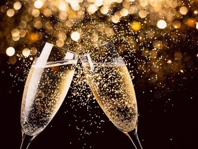 Two glasses of champagne toasting in the nigh with lights bokeh, glitter and sparks on the background