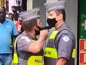 Police officer Felipe do Nascimento, left, points his gun at fellow officer Marcio Simao in a screengrab captured from video in Sao Paulo, Brazil, on Friday, Dec. 4, 2020.
