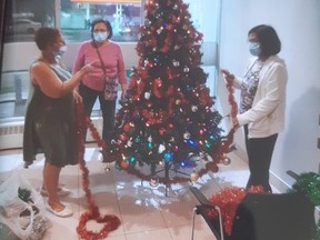 Residents of 855 Roselawn Ave. trim a Christmas tree in the lobby of their building, where a tree has been erected every holiday season for 25 years. But Toronto Community Housing Corporation has ordered the tree to be removed because of fire code violations and concerns over COVID-19 restrictions.