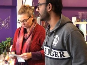 Barbara Bushe and partner Karthik Raj of The Point of Light, Body, Mind, Spirit Store & Centre in Newmarket receive a ticket for opening during York Region lockdown on Wednesday, Dec. 23, 2020.