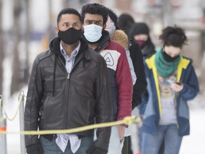People wear face masks as they wait to be tested for COVID-19 at a clinic in Montreal, Sunday, Jan. 3, 2021.