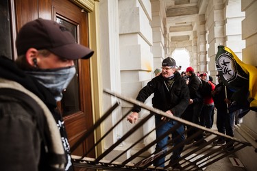 A member of a pro-Trump mob bashes an entrance of the Capitol Building in an attempt to gain access on January 6, 2021 in Washington, DC. 
(Photo by Jon Cherry/Getty Images)
