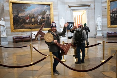 A pro-Trump protester carries the lectern of U.S. Speaker of the House Nancy Pelosi through the Roturnda of the U.S. Capitol Building after a pro-Trump mob stormed the building on January 06, 2021 in Washington, DC. 
(Photo by Win McNamee/Getty Images)