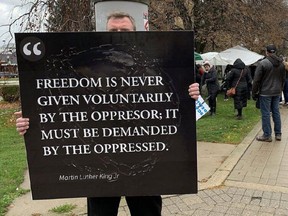 An anti-restrictions protester uses a famous quote about oppression from Martin Luther King Jr. to show how aggrieved he feels being forced to wear a mask during a small protest in Woodstock on Sunday Nov. 15, 2020. (Postmedia file photo)