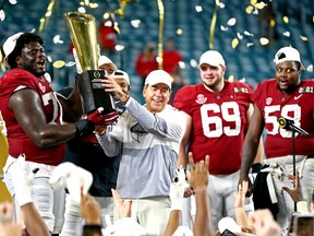 Alabama Crimson Tide head coach Nick Saban and offensive lineman Alex Leatherwood (70) celebrates with the CFP National Championship trophy after beating the Ohio State Buckeyes in the 2021 College Football Playoff National Championship Game Jan 11, 2021 in Miami Gardens, Florida, USA;