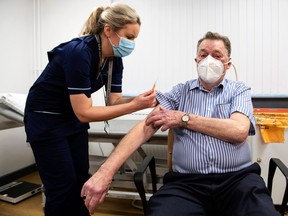 Advanced nurse practitioner Justine Williams (L) prepares to administer a dose of the AstraZeneca/Oxford Covid-19 vaccine to 82-year-old James Shaw, the first person in Scotland to receive the vaccination, at the Lochee Health Centre in Dundee on January 4, 2021.