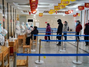 A medical worker takes a swab sample from a man as people queue to get tests for COVID-19 at an office building in Harbin, in northeastern China's Heilongjiang province on January 14, 2021.