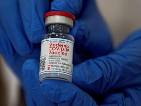 An employee shows the Moderna COVID-19 vaccine