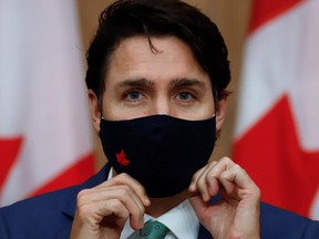 Canadian Prime Minister Justin Trudeau puts on a mask at a news conference in Ottawa