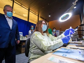 Ontario Premier Doug Ford watches a health-care worker prepare a Pfizer-BioNTech coronavirus disease (COVID-19) vaccine at The Michener Institute, in Toronto, Canada January 4, 2021.