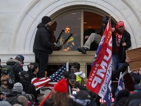 A mob of supporters of U.S. President Donald Trump climb through a window they broke as they storm the U.S. Capitol Building in Washington, Jan. 6, 2021.
