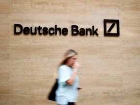 In this file photo taken July 8, 2019, a pedestrian walks past a logo outside the offices of German bank Deutsche Bank in London, England.