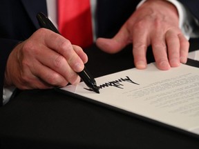 U.S. President Donald Trump signs executive orders extending coronavirus economic relief, during a news conference in Bedminster, N.J., Aug. 8, 2020.