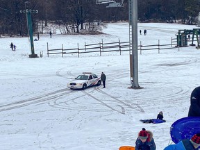 A parent speaks with a police officer parked at the bottom of the ski hill at Earl Bales Park in Toronto on Sunday, Jan. 3 2021.