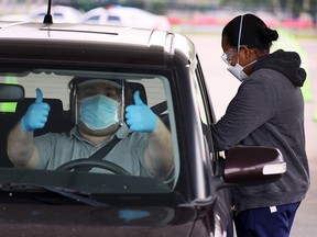 A driver gives the thumbs up as his passenger is given a COVID-19 vaccination by a healthcare worker at a drive-thru site at Tropical Park on January 13, 2021 in Miami.