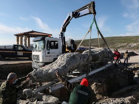 Workers lift a fossilized tree, part of a petrified forest, with a crane on the island of Lesbos, Greece, December 19, 2020.